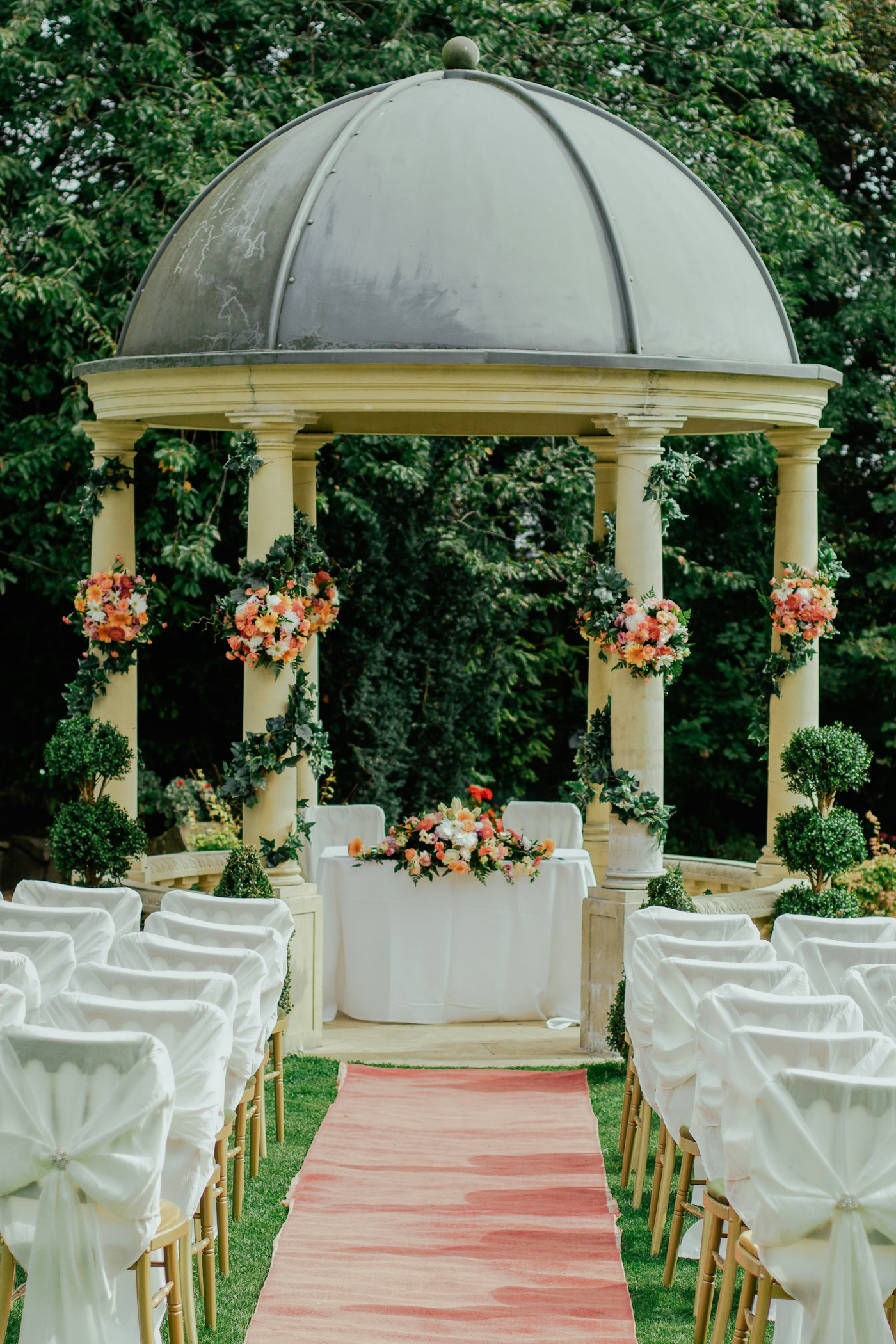 Floral ceremony pavilion surrounded by a lush green garden